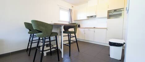 A kitchen with white cabinets, a stainless steel oven, and a trash bin.