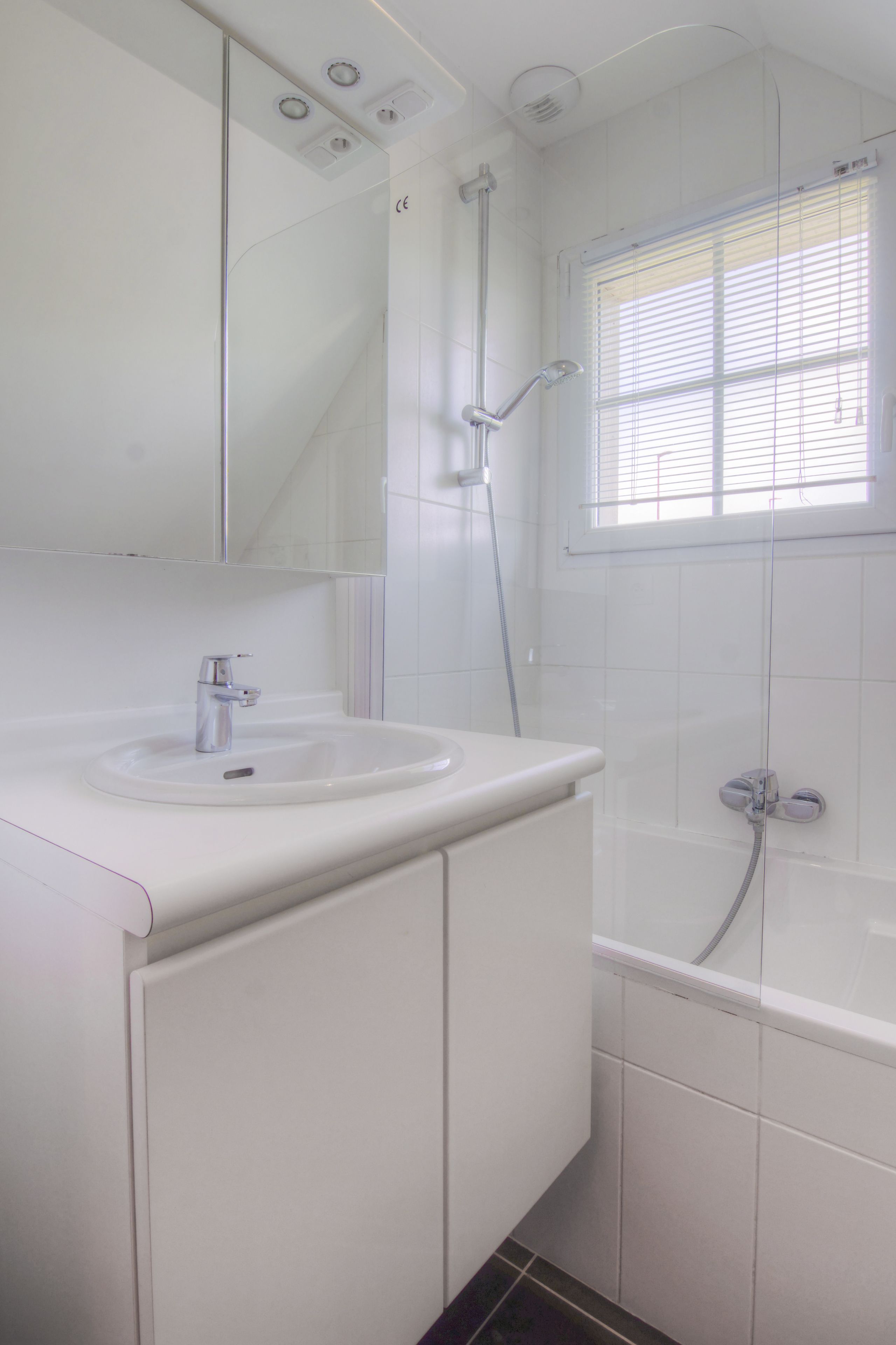 A modern bathroom with a sink, mirror, and shower.