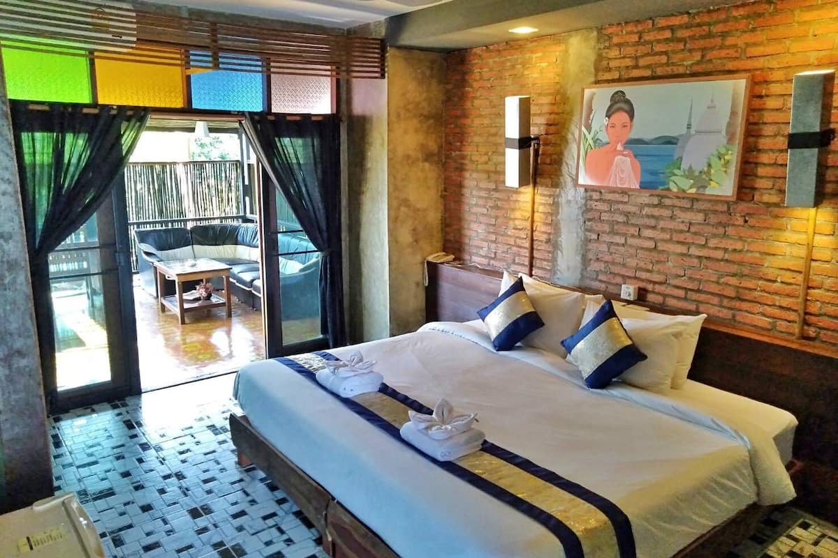 Quarto de hotel com cama, escrivaninha, cadeira e vista para o exterior.