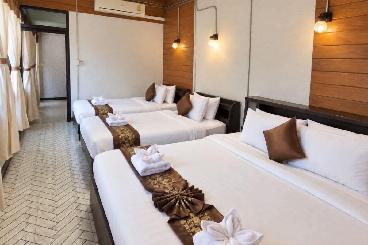 A hotel room with three beds, each with a neatly made bedspread and pillows.