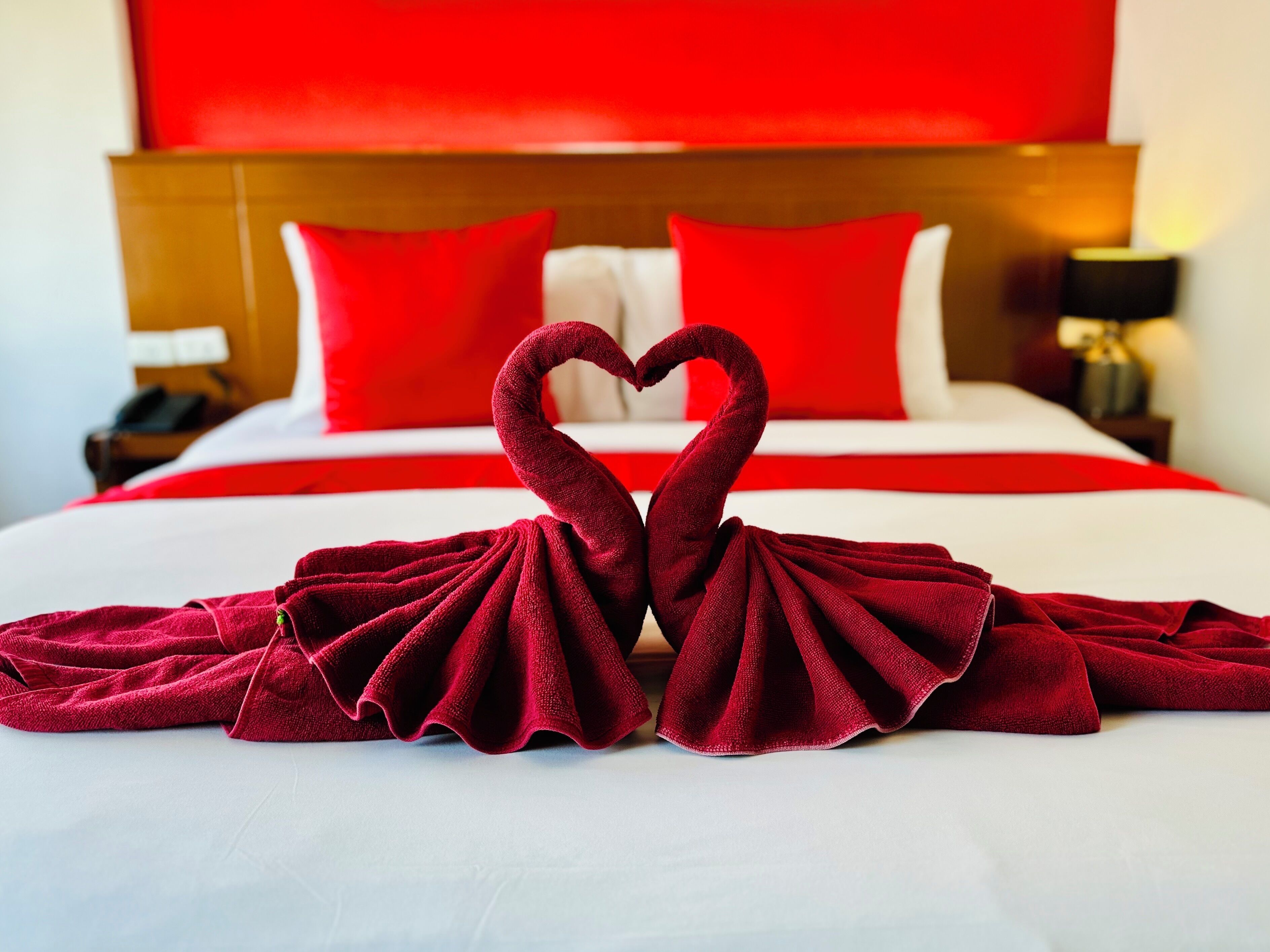 A bed with a heart-shaped towel arrangement in the center.