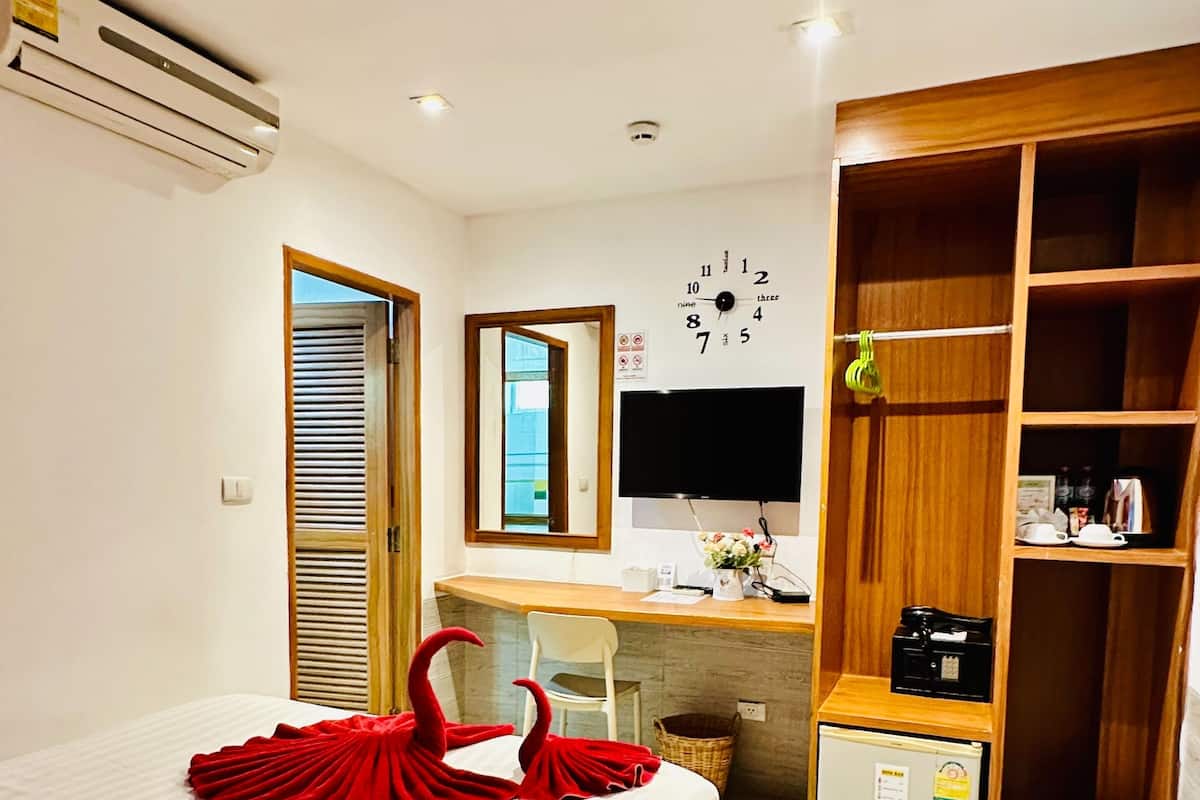 A hotel room with a bed, a desk, a wardrobe, and a TV.
