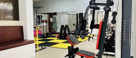 A gym with a bench, weight machines, and a mirrored wall.