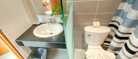Un baño con lavamanos, inodoro y cortina de ducha.