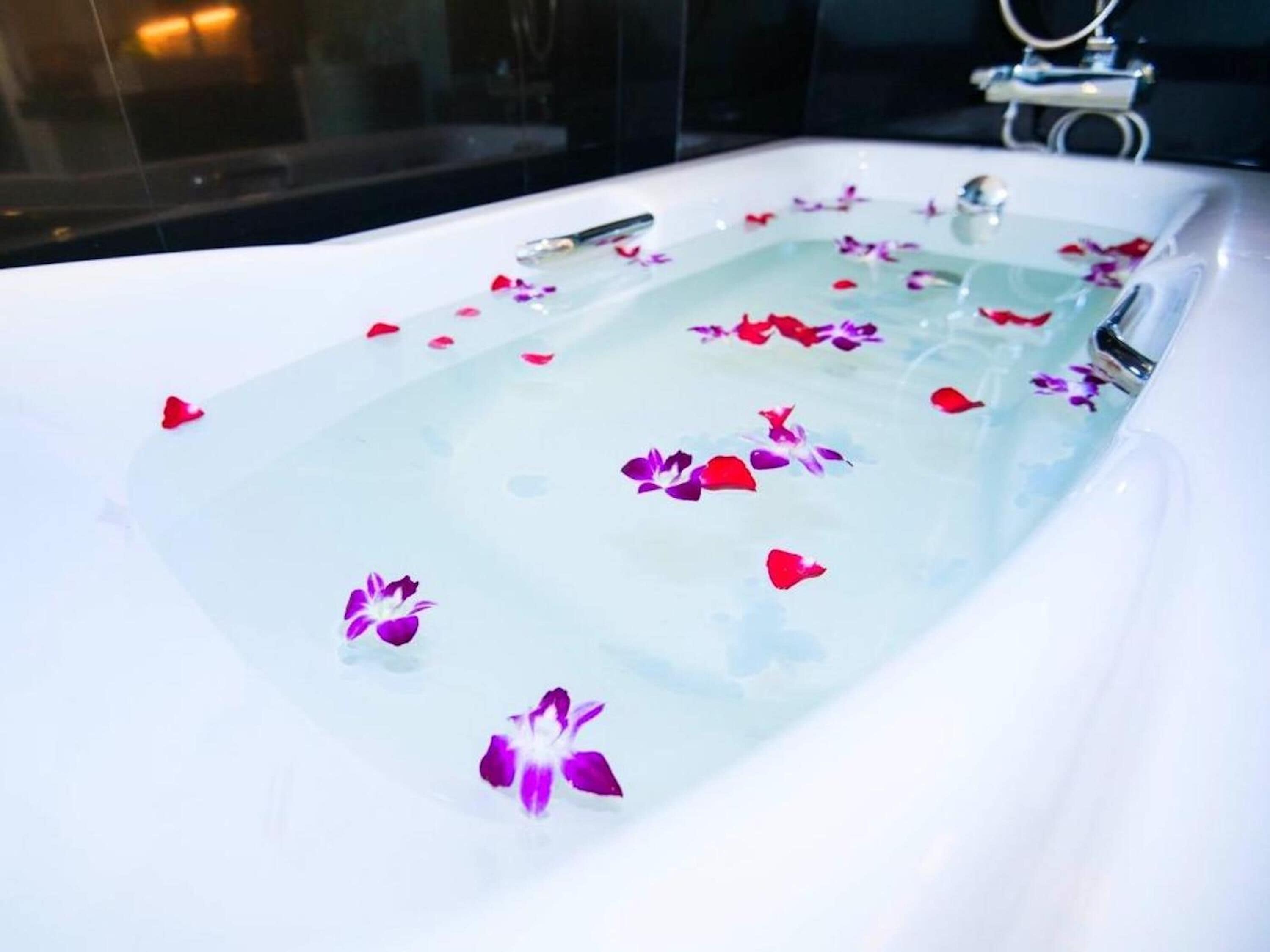 Una bañera llena de agua y pétalos de rosa.