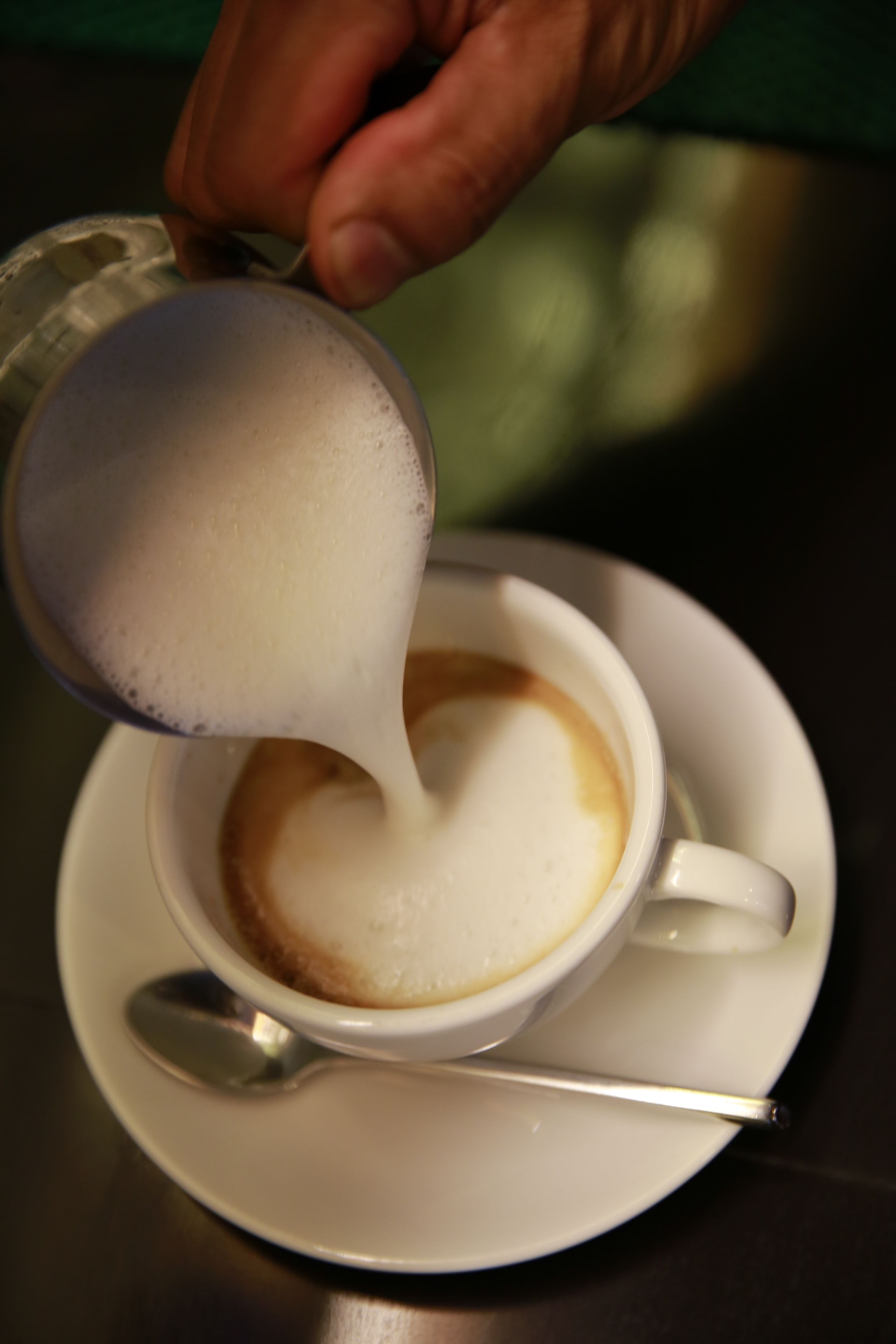 Se vierte leche en una taza de café.