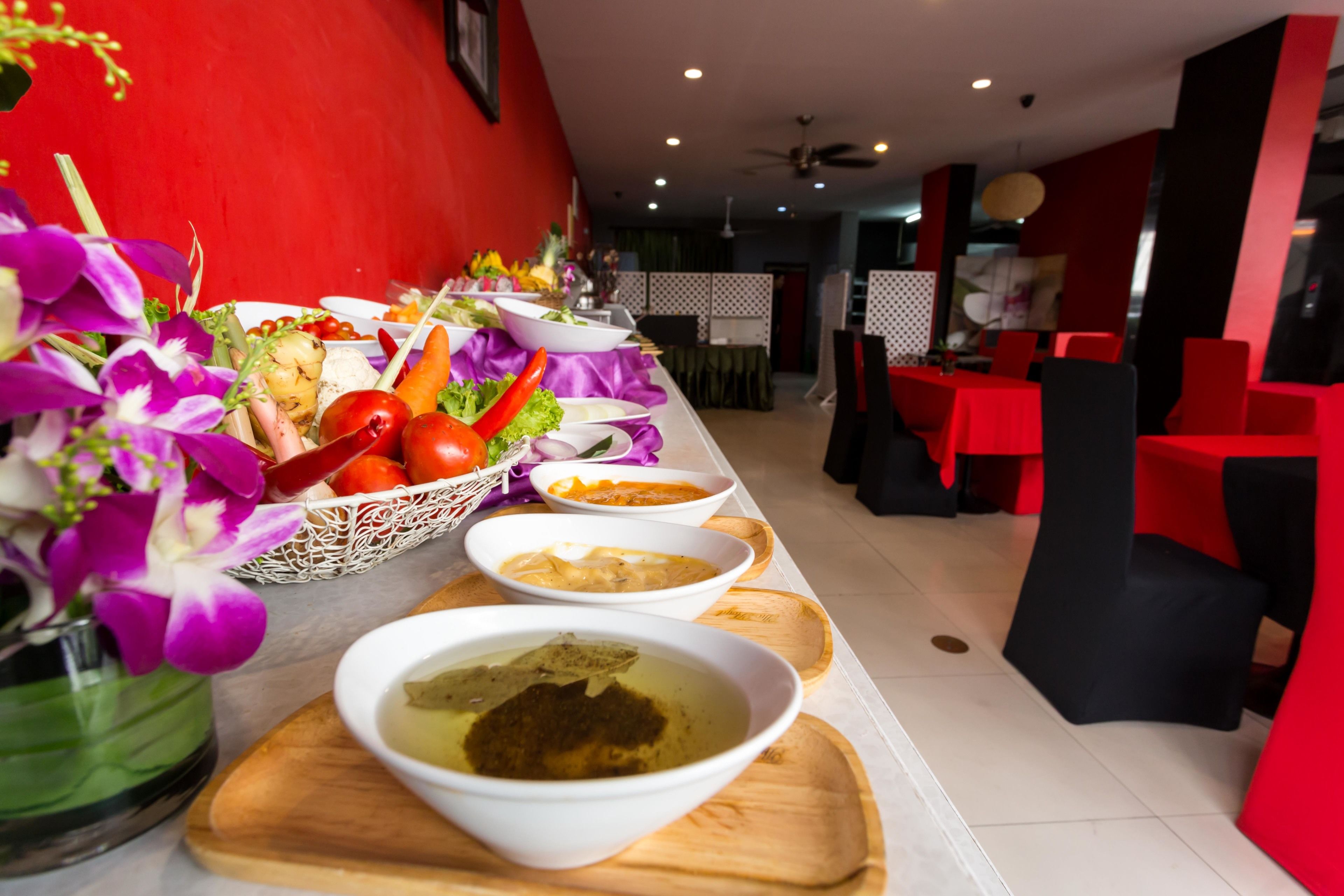 A buffet setup with various dishes and a decorative vase of purple flowers.