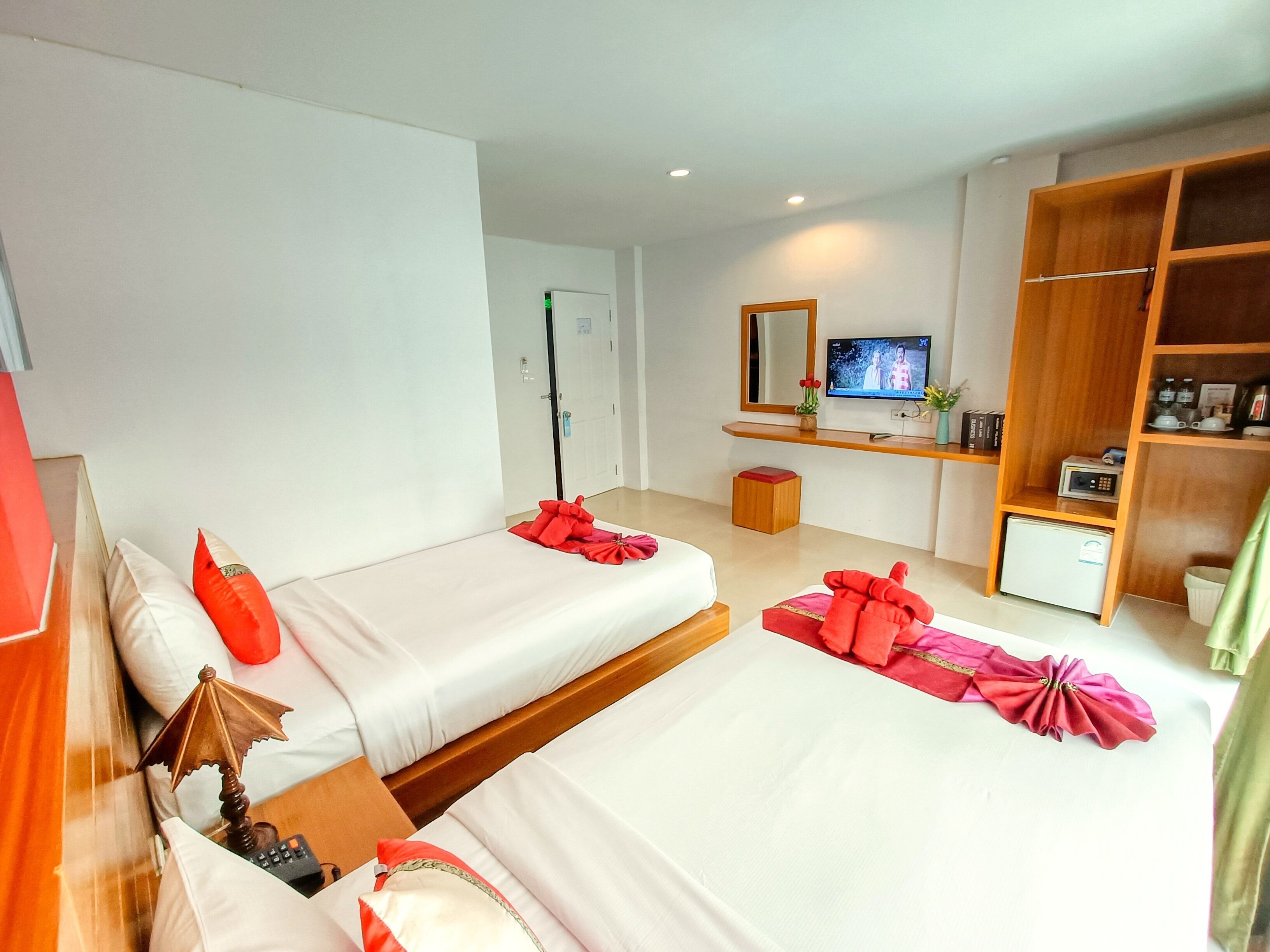 Une chambre d’hôtel avec deux lits, une télévision, une armoire en bois et une petite table avec une télécommande.