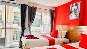A hotel room with two beds, a red accent wall, and a large window with curtains. - PJ Patong Resortel (Patong)