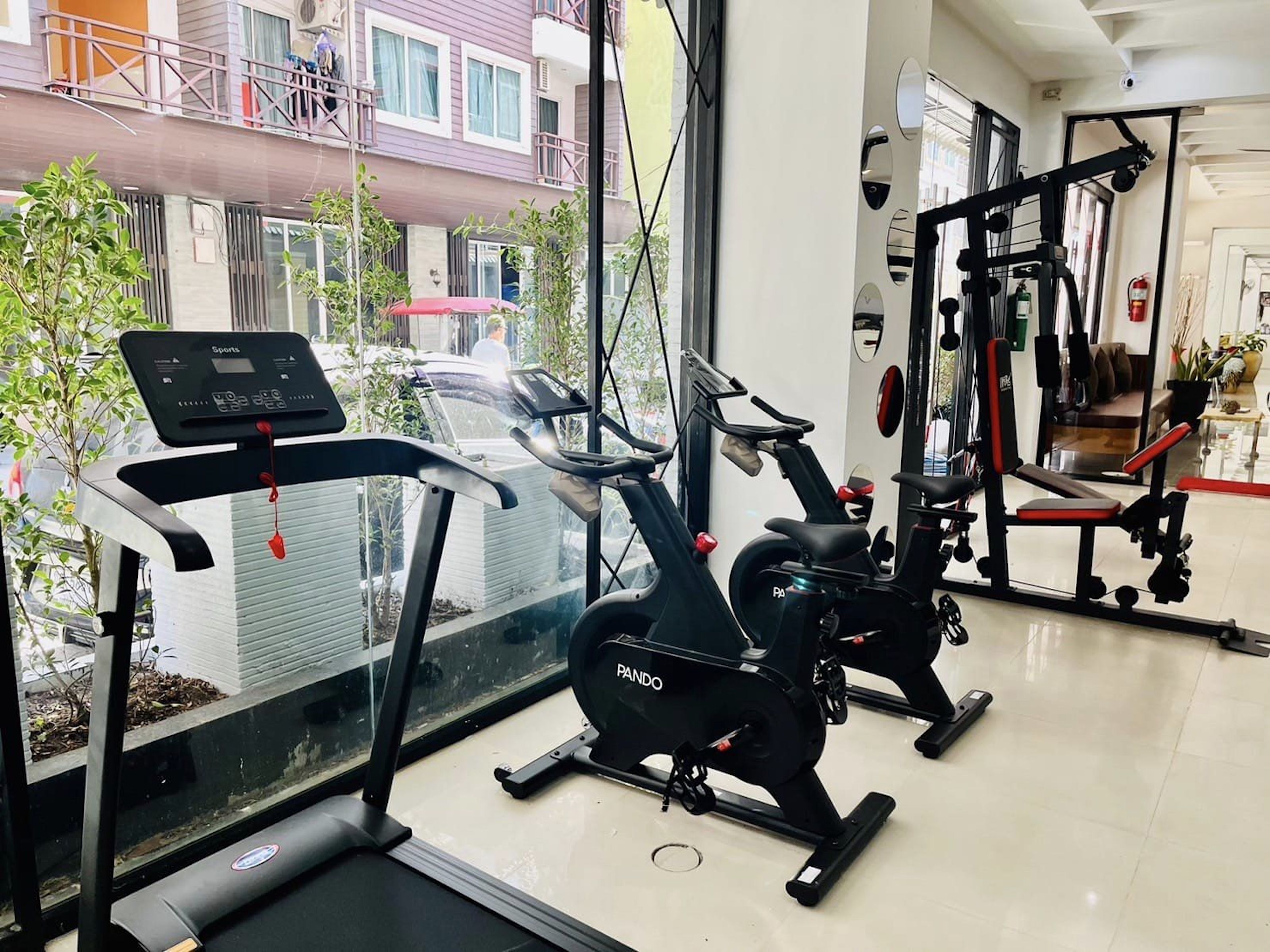 Une salle de sport équipée de machines de cardio, d’appareils de musculation et dotée d’un mur recouvert de miroirs.