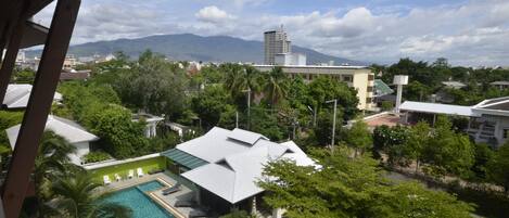 A residential area with a swimming pool, a tall building in the background, and lush greenery.