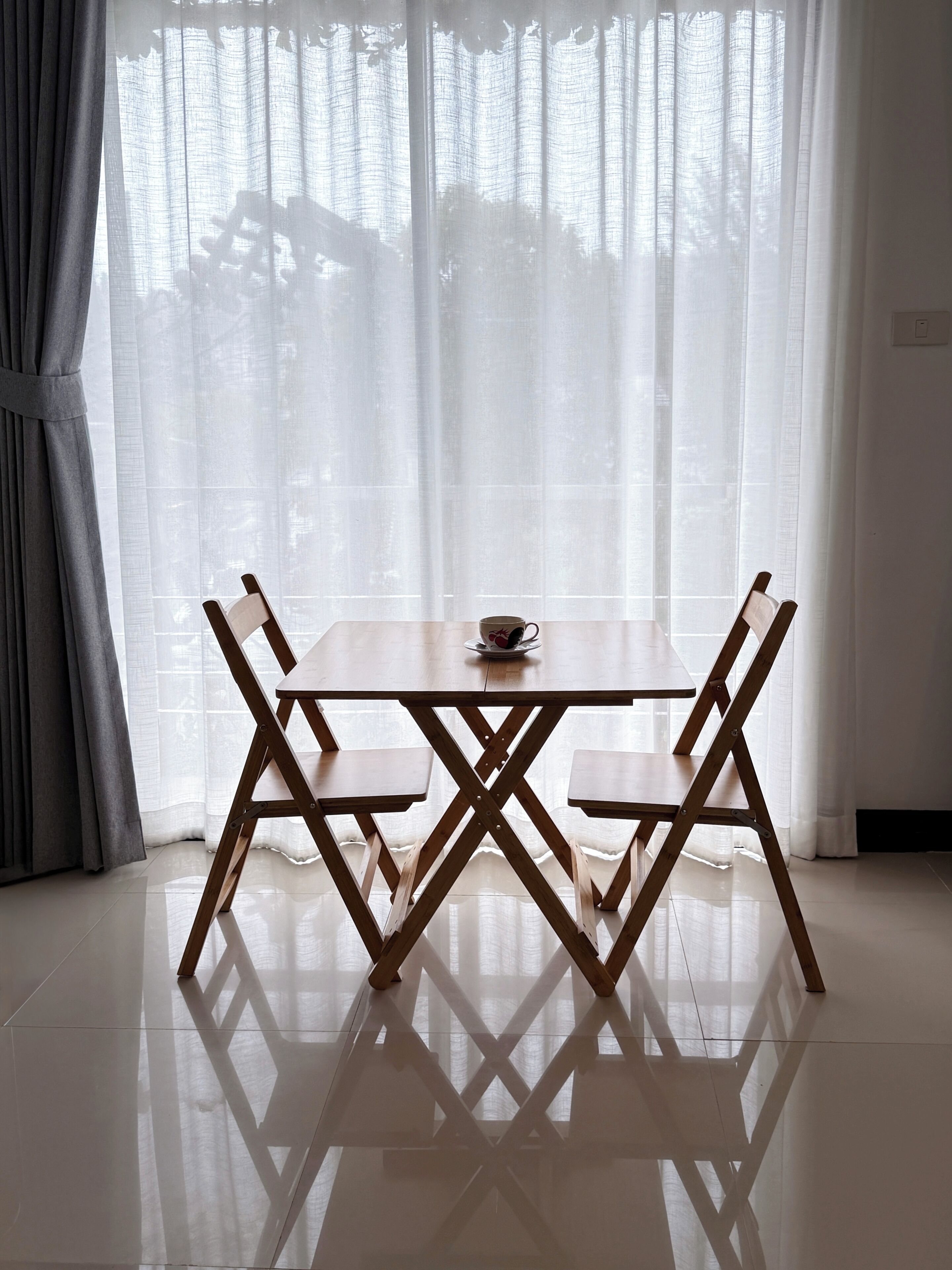 A dining table with chairs, a cup, and a bowl on the table.