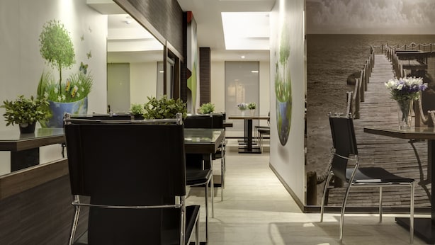 Un moderno vestíbulo de hotel con una recepción, un área de estar y una escalera que conduce a un nivel superior.