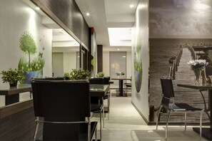 Eine moderne Hotelhalle mit einer Rezeption, einer Sitzecke und einer Treppe zu einer oberen Ebene.