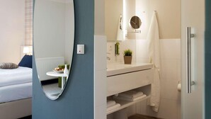 Een moderne slaapkamer met een grote spiegel, een nachtkastje en een bed.