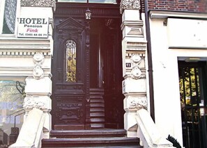 A black double door with a glass panel, flanked by white columns with decorative capitals. A sign above the door reads "HOTEL Pension Fink" with a telephone number. - Hotel-Pension Fink (Hamburg)