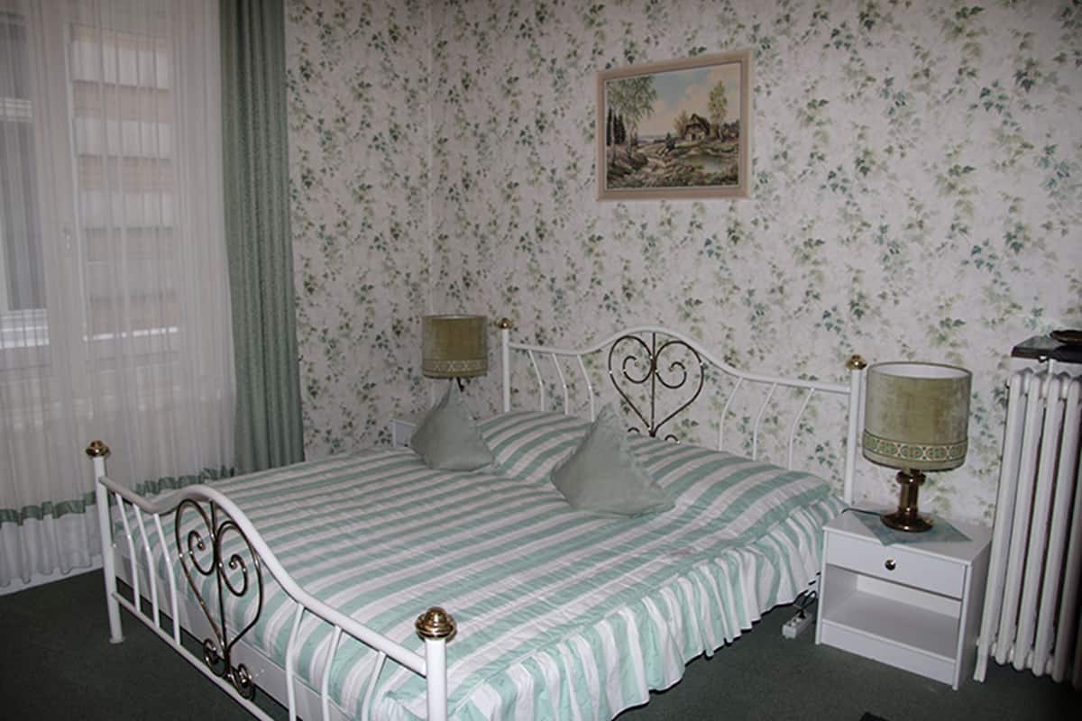 A bedroom with a bed, nightstand, and a lamp.