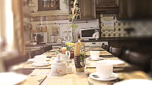 A dining table set with white cups, saucers, a teapot, and a bottle of liquor. - Hotel-Pension Fink (Hamburg)