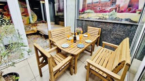 A wooden table set for four with plates and glasses, a painting of a cityscape, and a potted plant. - The Melville Hotel by Rokxy - Kings Cross (London)
