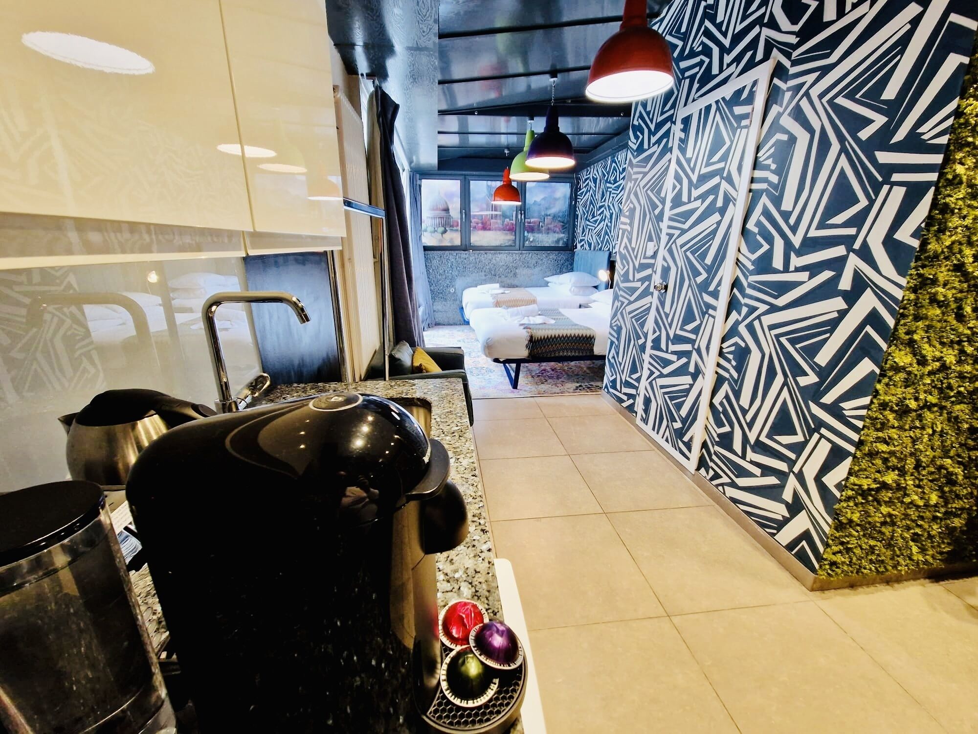 Eine moderne Küche mit Kaffeemaschine, Spüle und Fensterblick auf ein Schlafzimmer.