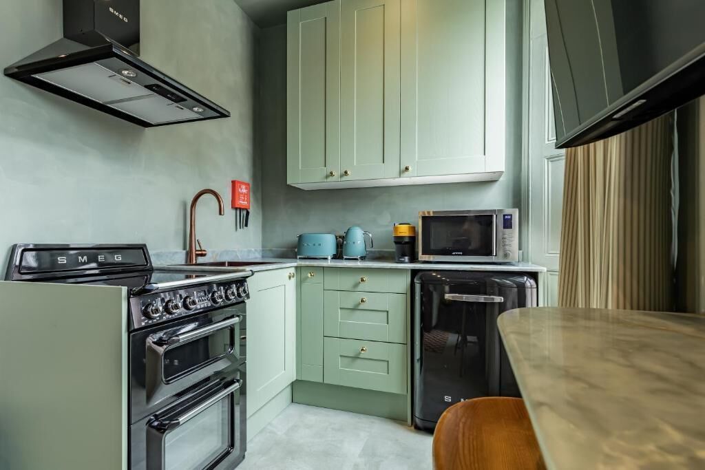 A compact kitchen with a stove, oven, microwave, and a small refrigerator.