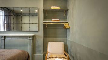 A room with a bed, a chair, a fireplace, and shelves with books.