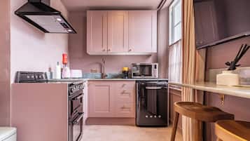 A compact kitchenette with a built-in oven, microwave, and a coffee machine.