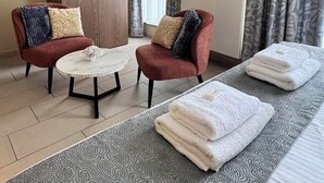 A hotel room with a bed, two armchairs, a wooden wardrobe, a round table, and a patterned rug. - Hotel José (Blankenberge)