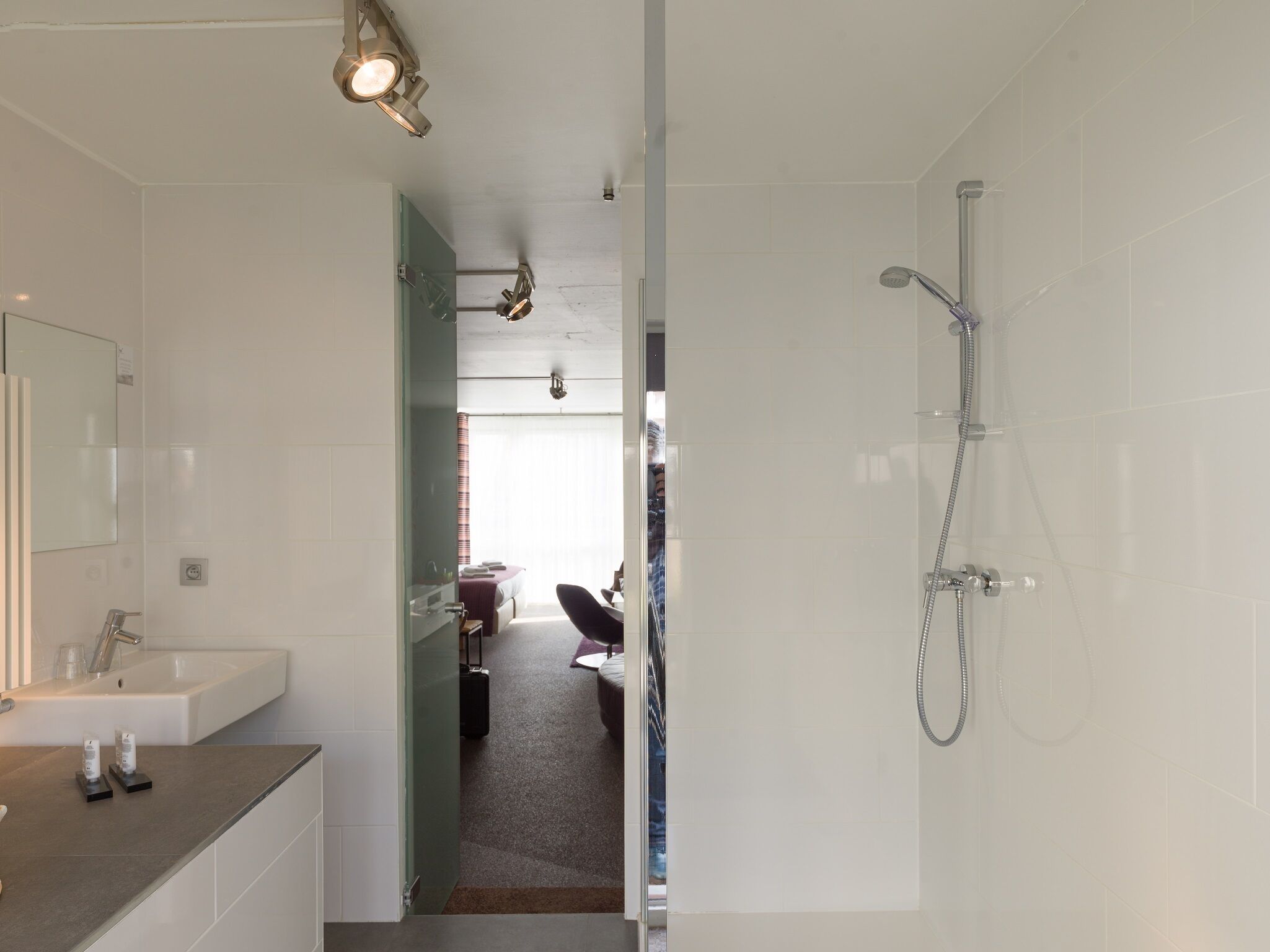 Une salle de bain moderne avec un grand miroir, un lavabo et une douche.