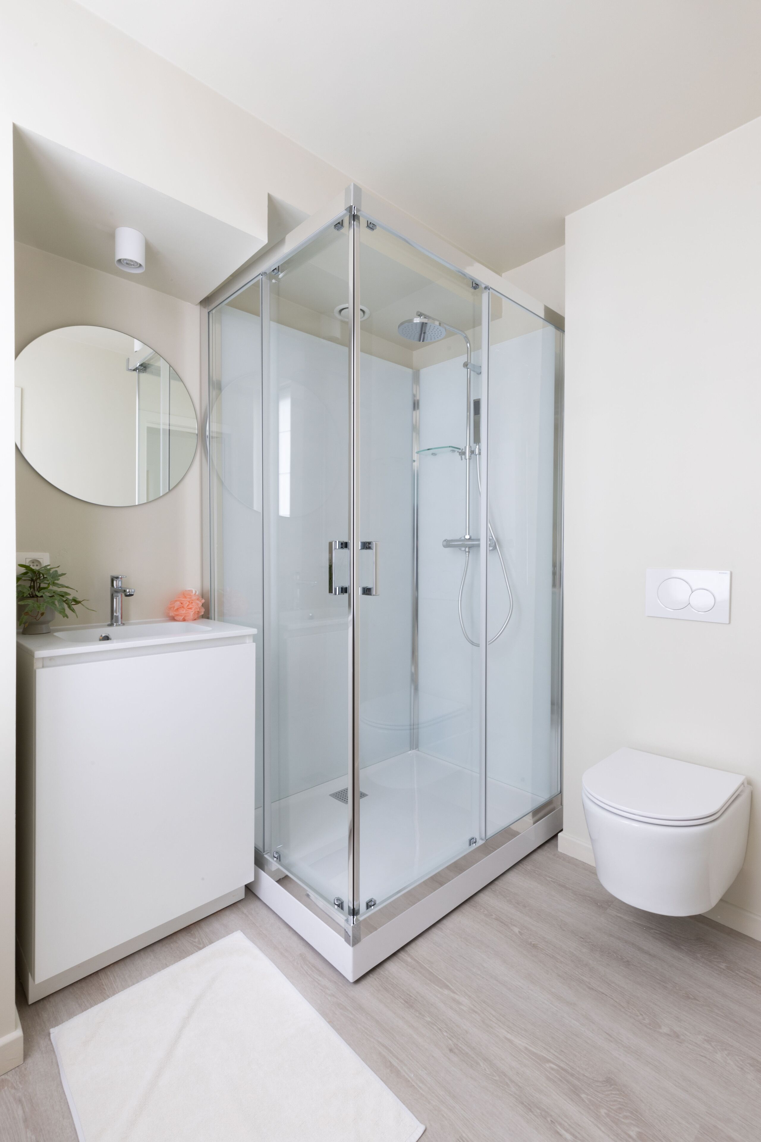 Een moderne badkamer met een douchecabine van glas, een witte wastafel en een toilet.
