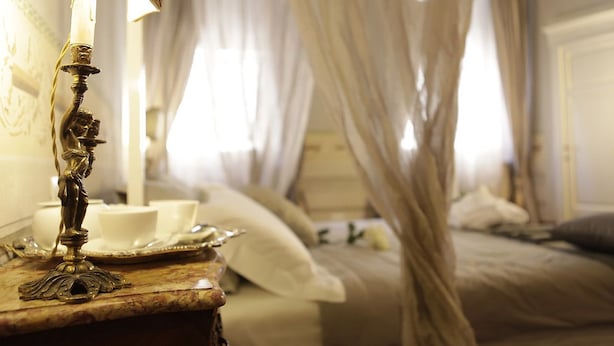 A bedroom with a bed, a bedside table with a lamp, and a canopy bed. - Residenza d'Epoca - B&B Santa Caterina (Pisa)