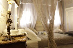 Un dormitorio con cama, una mesita de noche con lámpara y dosel.