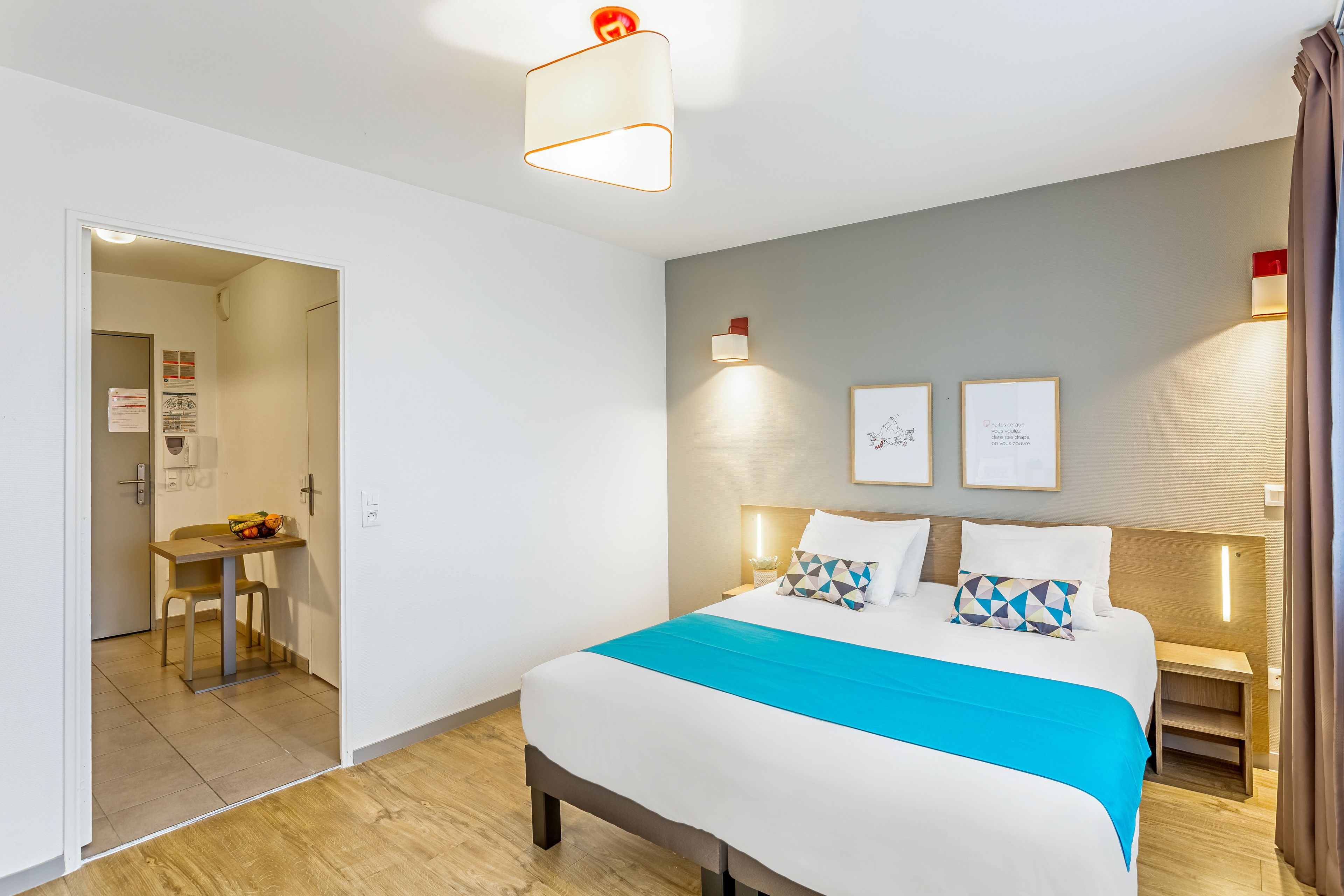 Een moderne hotelkamer met een groot bed, een bureau met stoel, en een zithoek.