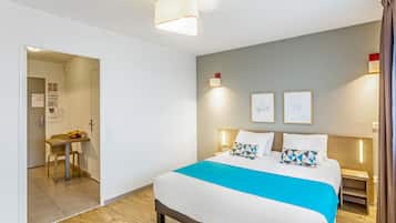 Een moderne hotelkamer met een groot bed, een bureau met stoel, en een zithoek.