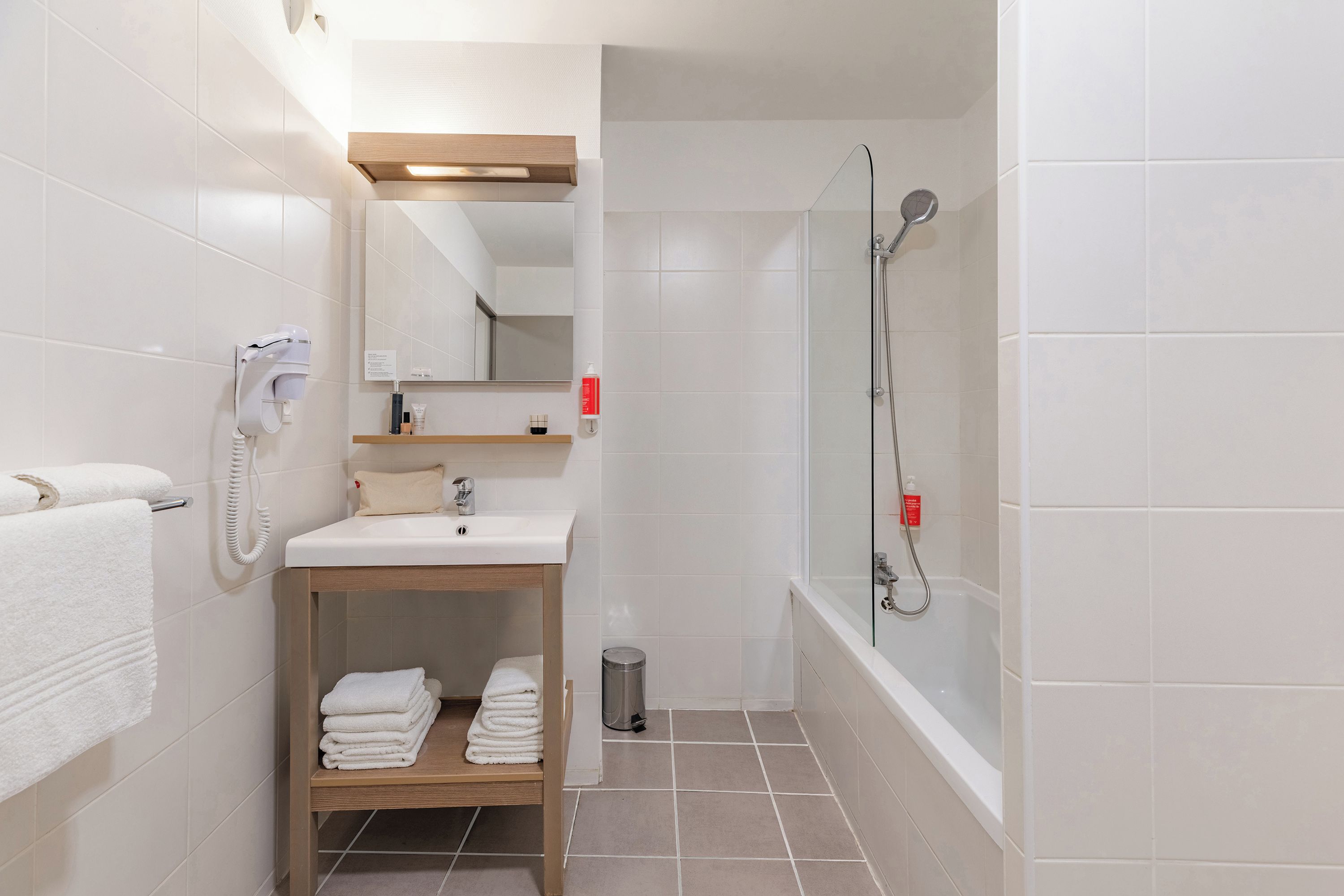 Une salle de bain moderne équipée d’un lavabo, d’un miroir, d’un porte-serviettes et d’une douche à l’italienne.