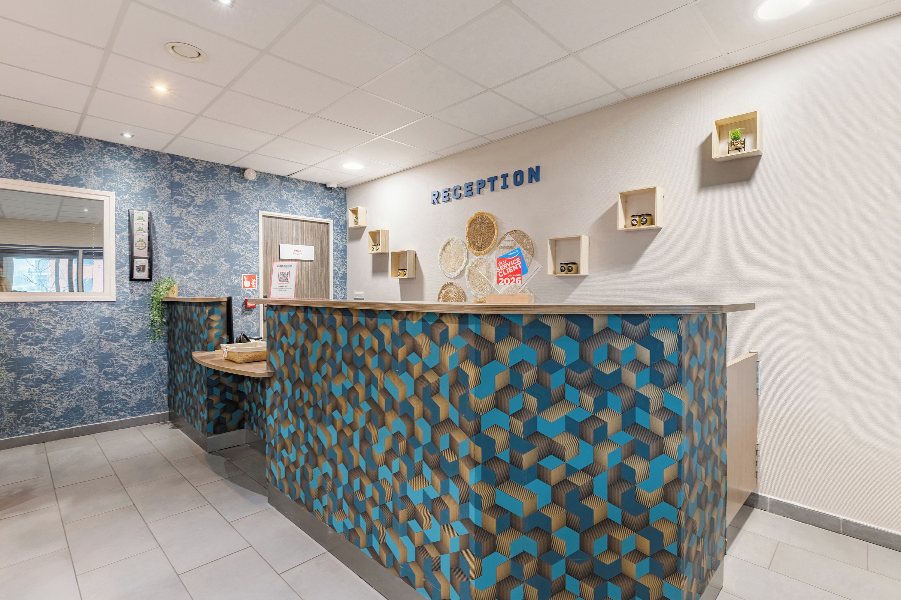 A reception area with a geometric patterned wall, a reception desk, and a wall-mounted sign.