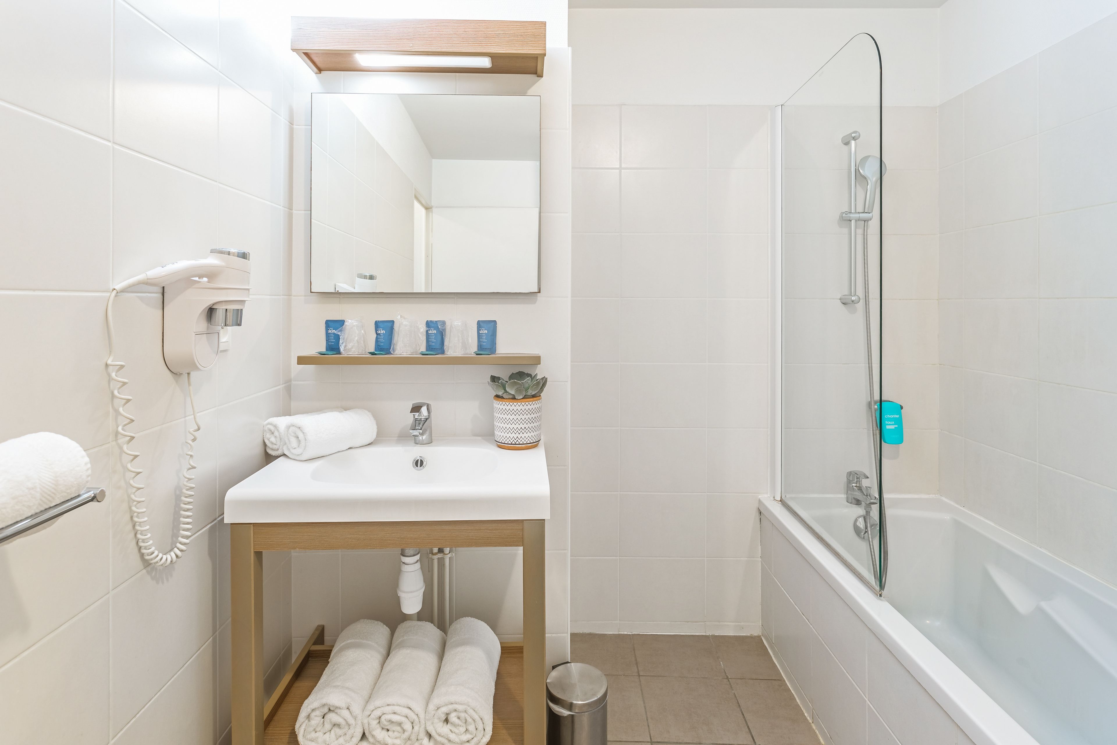 Une salle de bain moderne avec un lavabo blanc, un miroir et une douche.