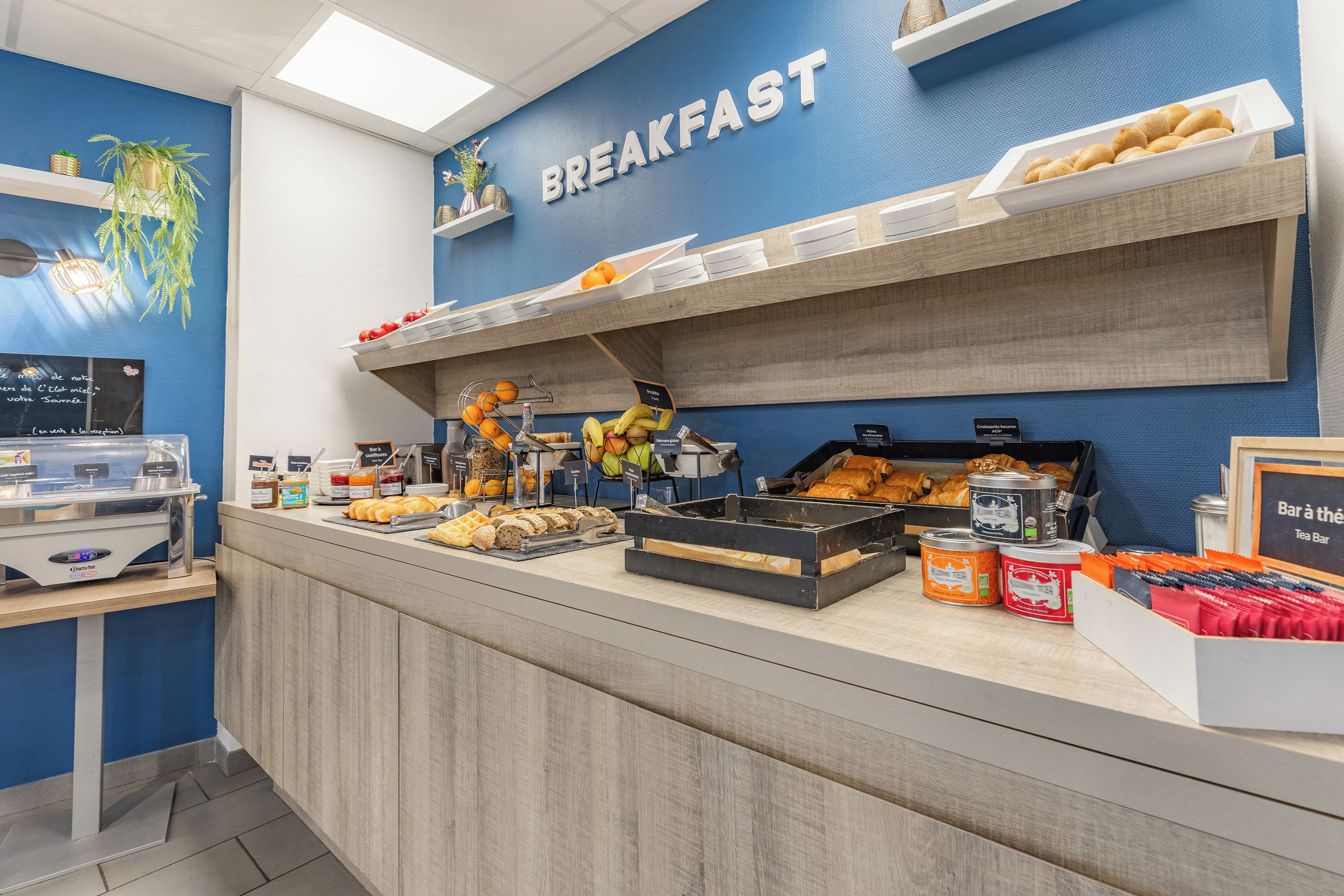 En frukostbuffé med ett varierat utbud av mat och en skylt med texten ”FRUKOST”.