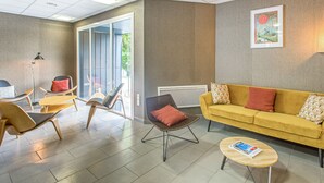 Een moderne woonkamer met een gele bank, houten stoelen en een salontafel.