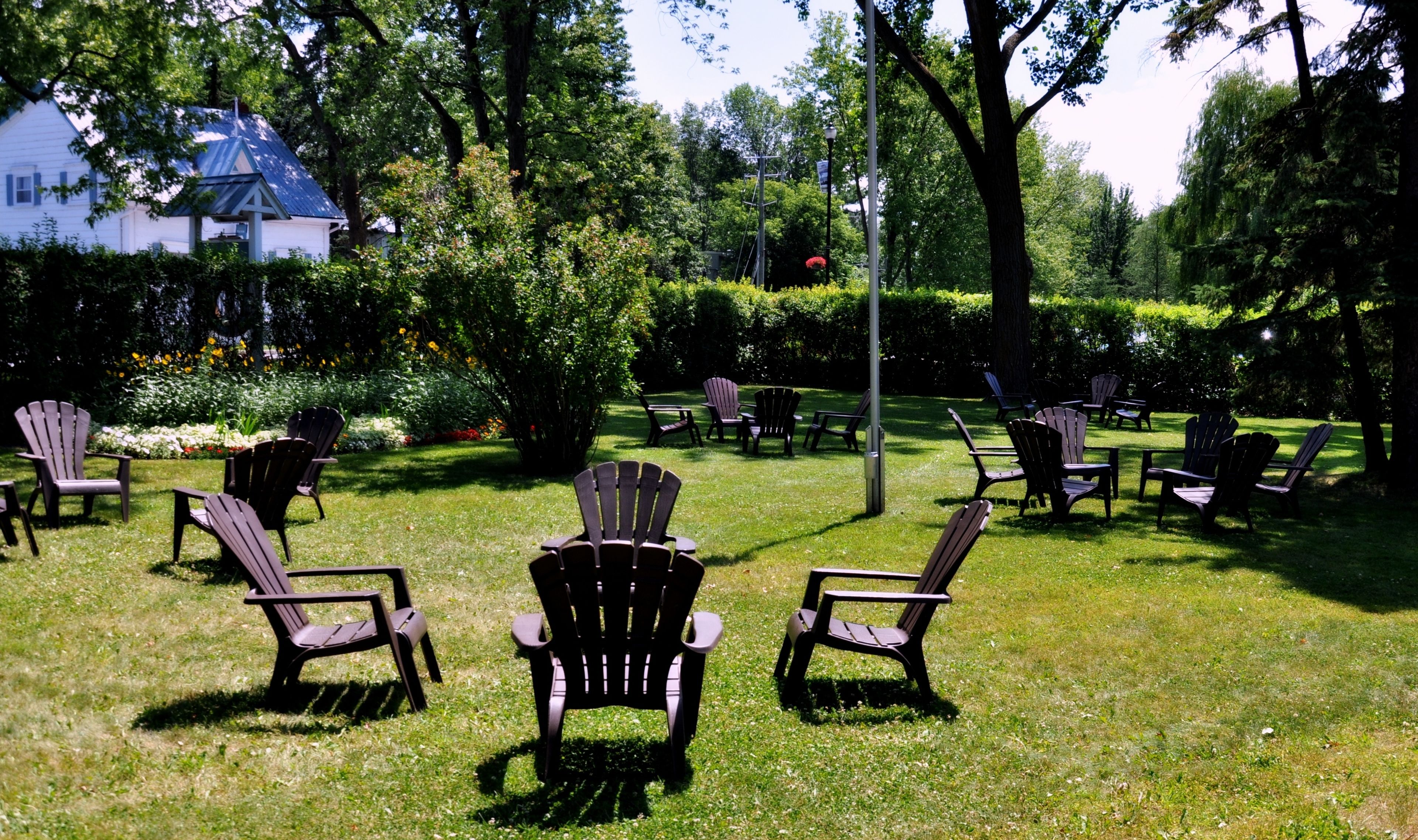 A grassy outdoor area with several Adirondack chairs arranged for seating.