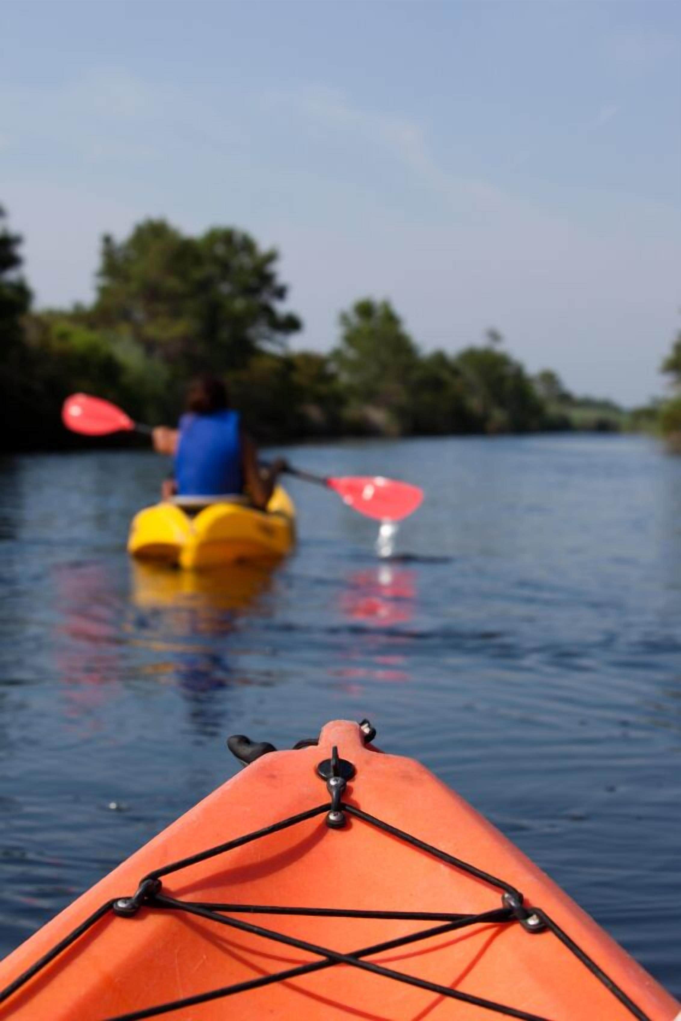 Una canoa en aguas tranquilas, con una persona remando al fondo.