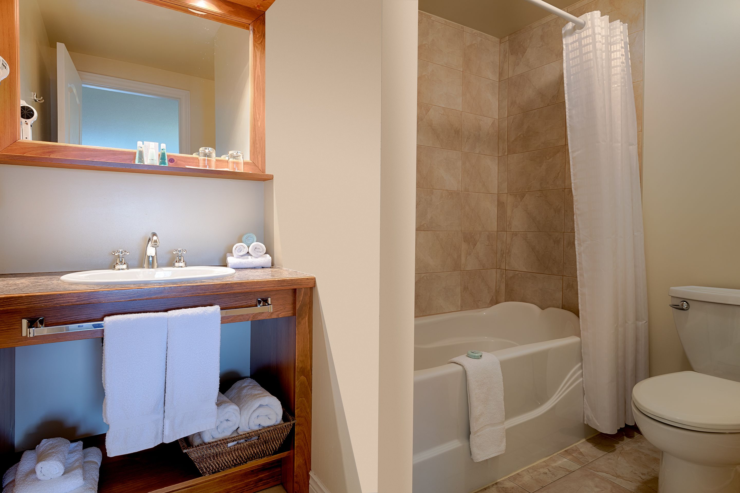 A bathroom with a sink, mirror, and a bathtub.