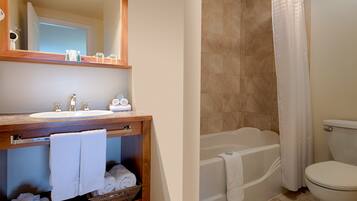 A bathroom with a sink, mirror, and a bathtub.