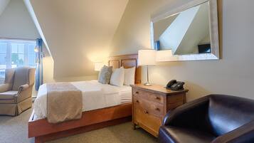 Une chambre à coucher avec un grand lit, des tables de chevet, une chaise, un miroir et une fenêtre avec des rideaux.