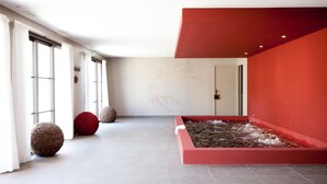 Un interior moderno con una pared roja destacada, un elemento de agua y un diseño minimalista.
