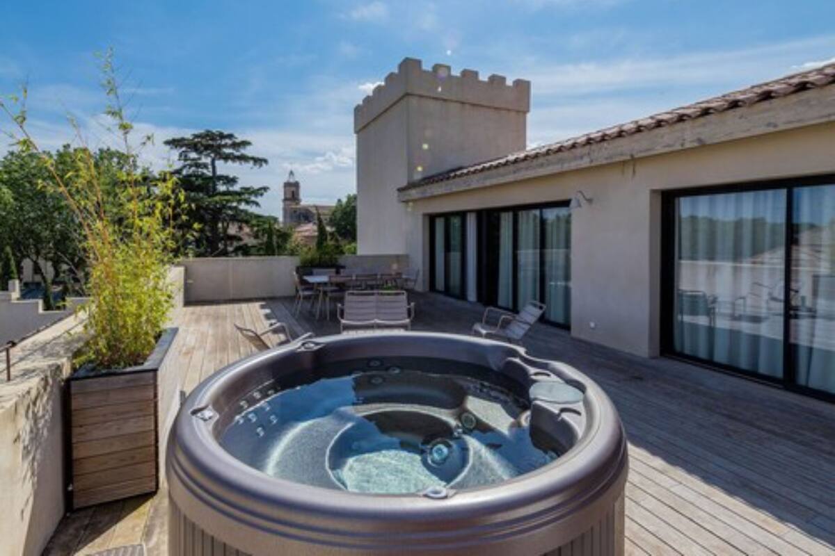 Una azotea con jacuzzi, mobiliario exterior y vistas a un edificio que recuerda a un castillo.