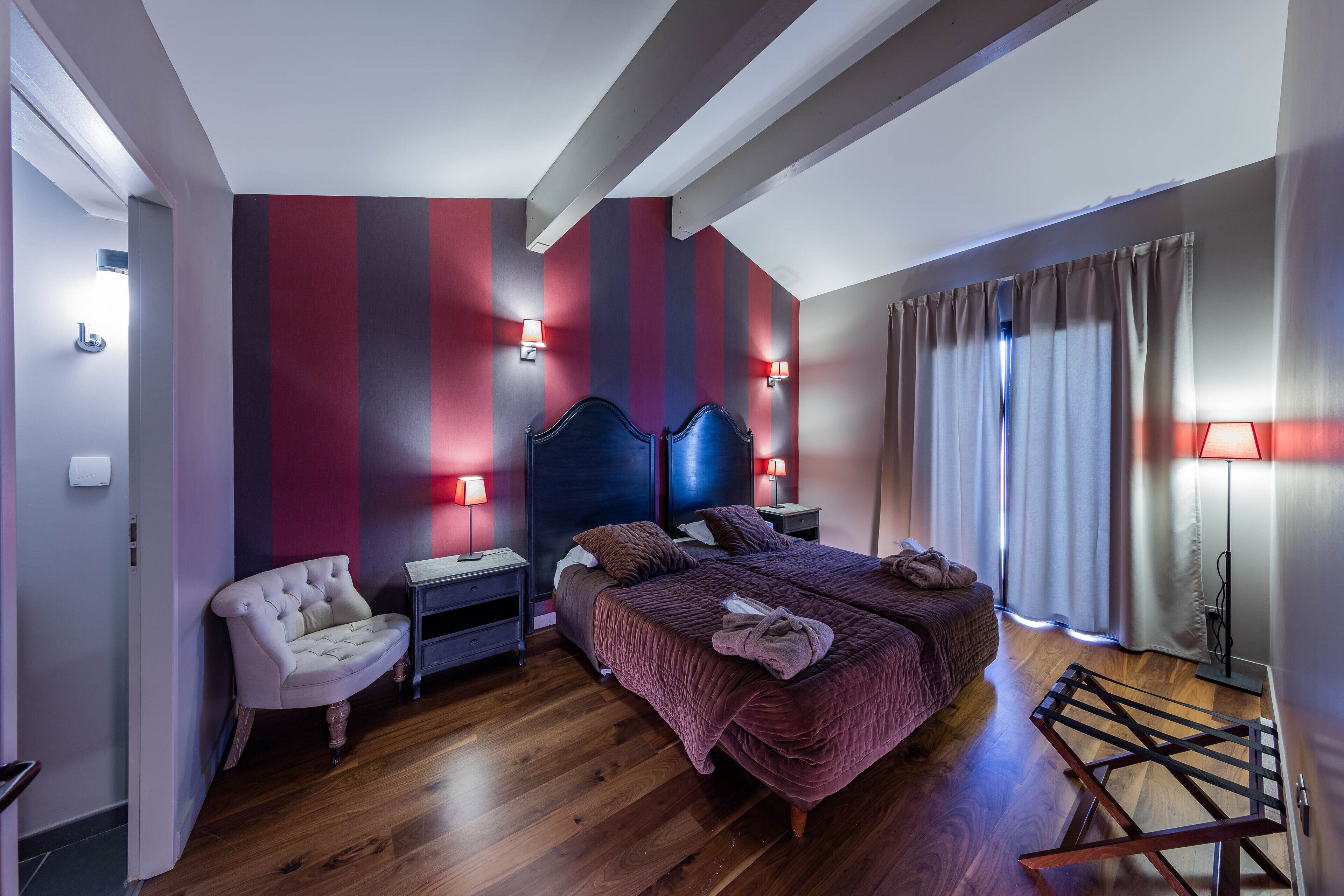 A bedroom with a bed, bedside tables, a chair, and a wardrobe.