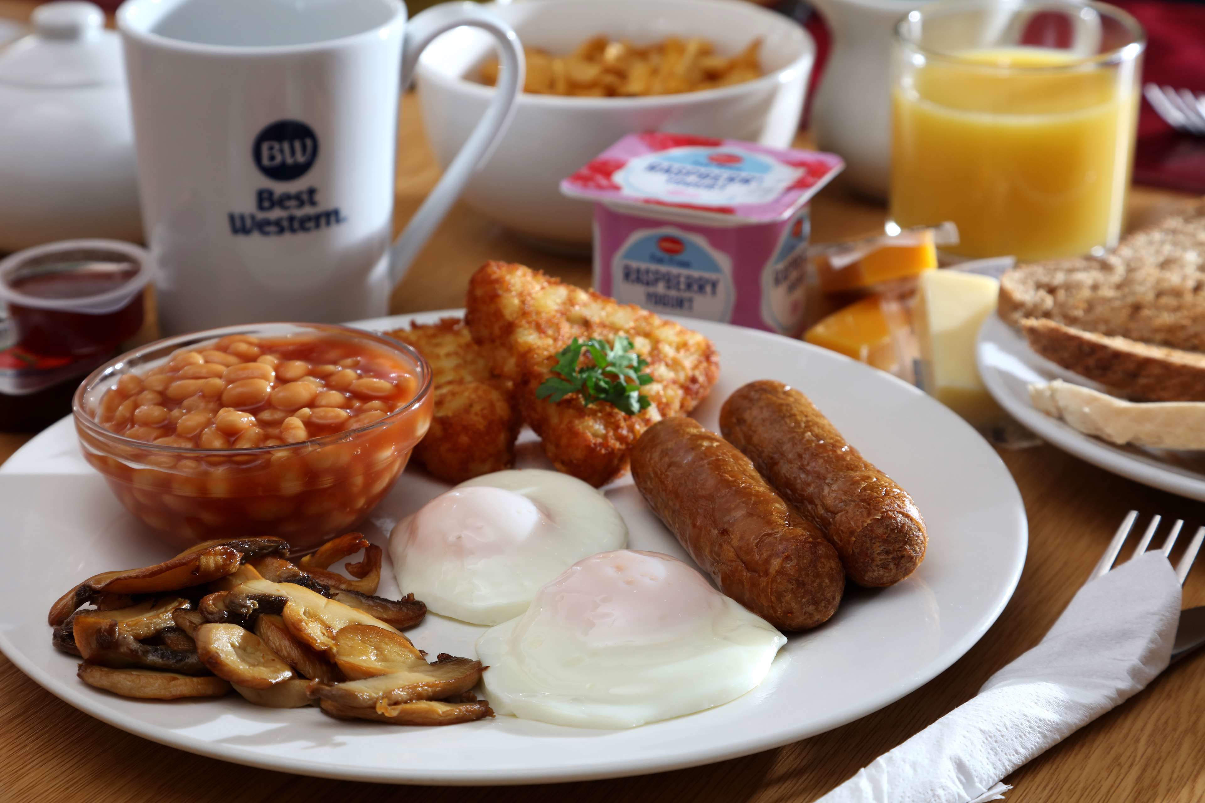 A breakfast plate with eggs, sausages, mushrooms, beans, and toast.