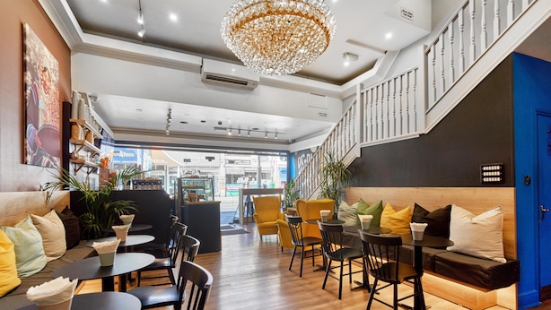 A modern interior with a staircase, seating areas, and a view of the street.