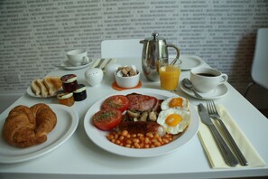 A breakfast table with plates of eggs, bacon, tomatoes, beans, and a croissant. - B+B Belgravia (London)
